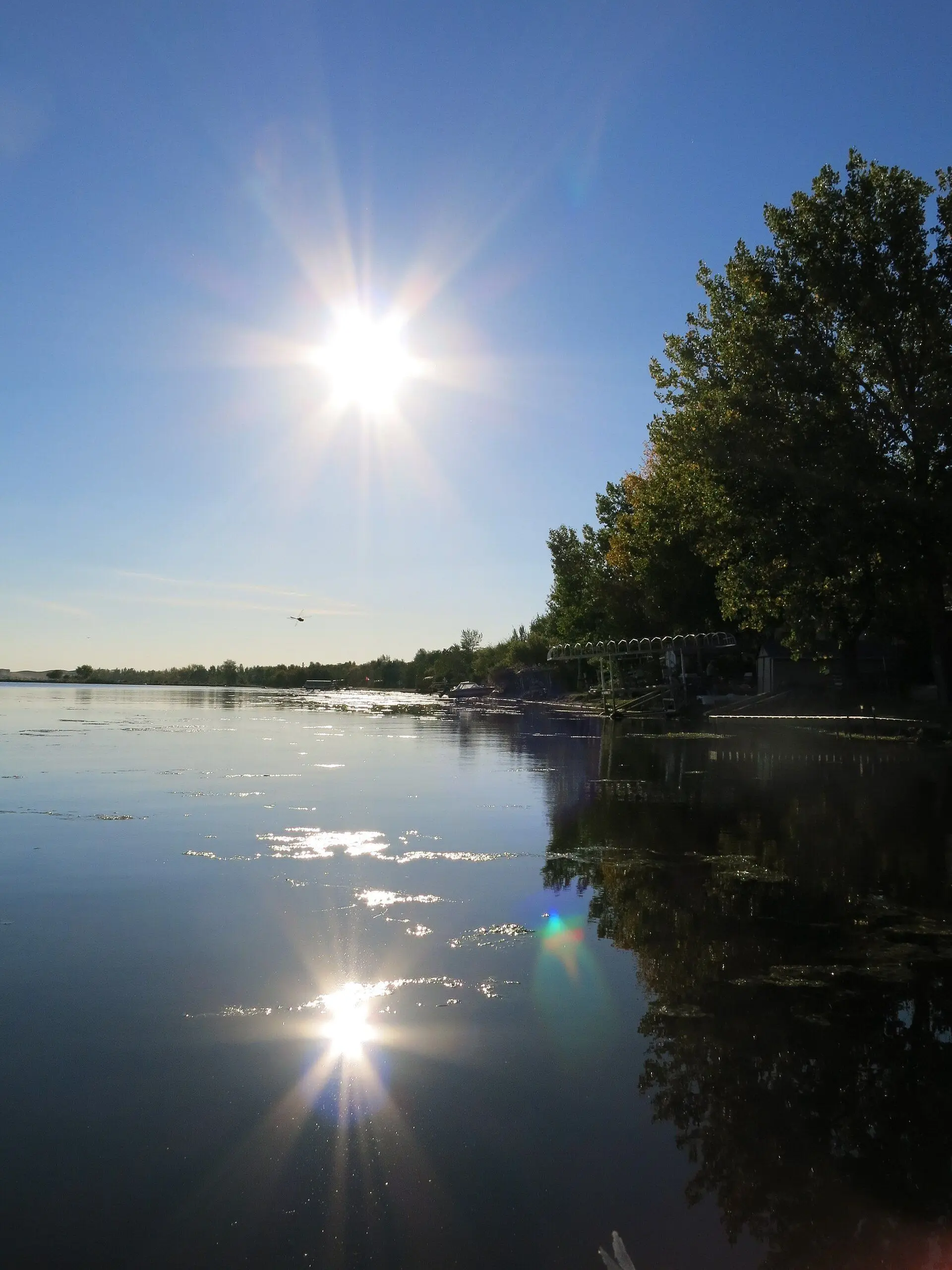 Sun over Jackfish Lake with boat lifts along the shore