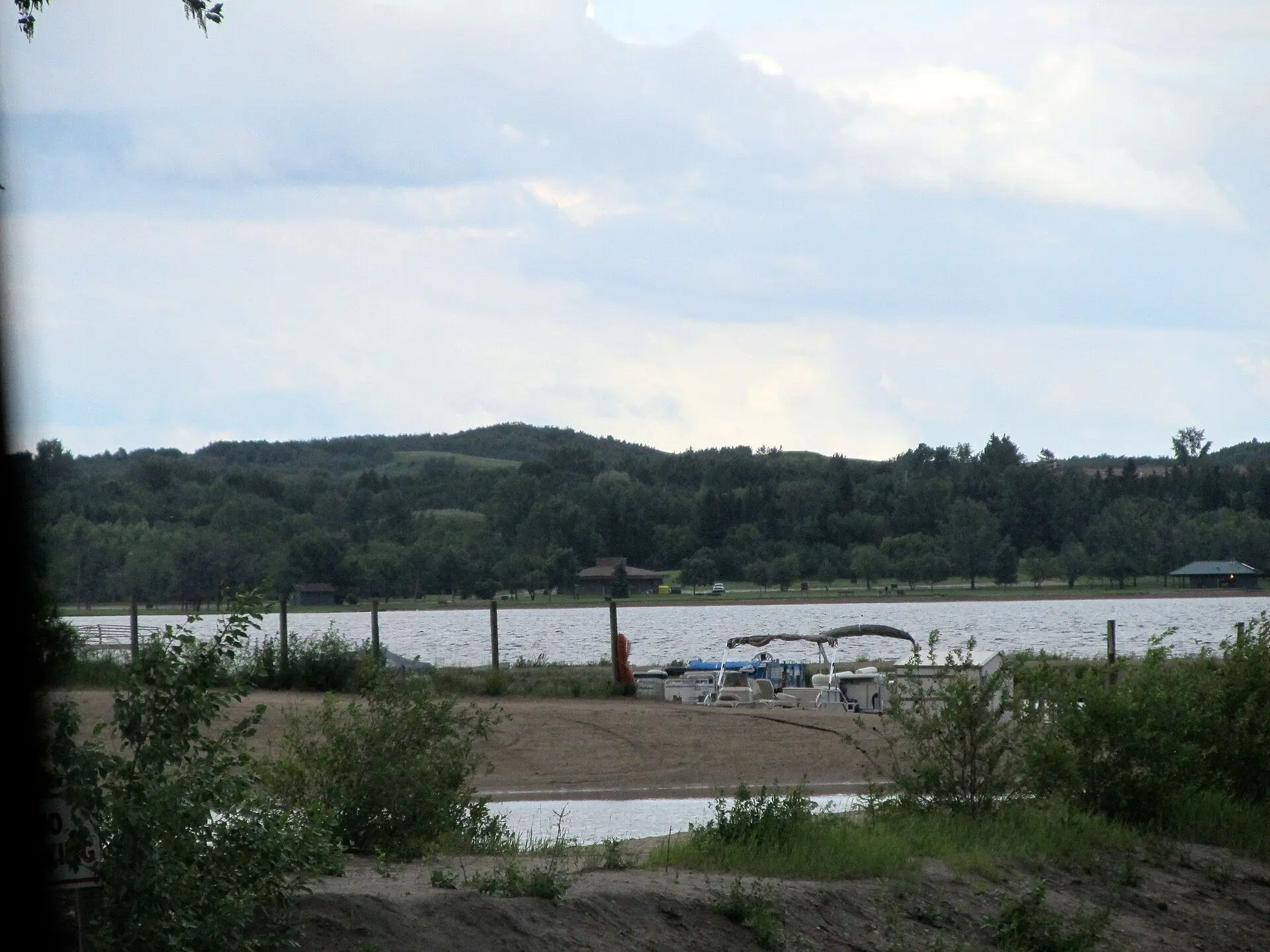 Jackfish Lake shoreline with pontoon boat and wooded hills