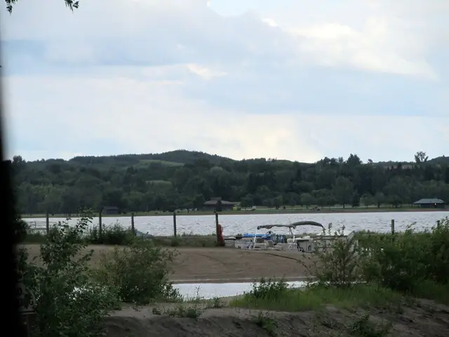 Jackfish Lake shoreline with pontoon boat and wooded hills